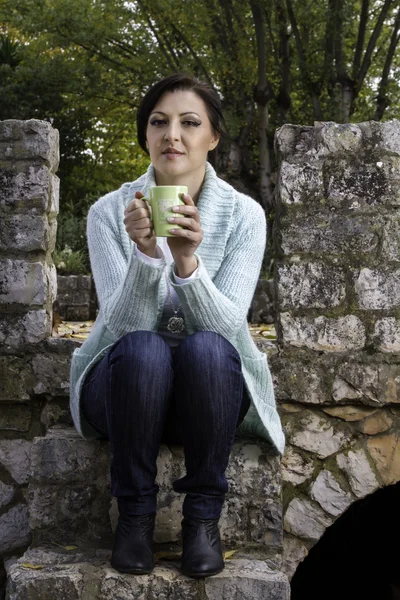 Jonge mooie vrouw het drinken van thee op een stadspark — Stockfoto