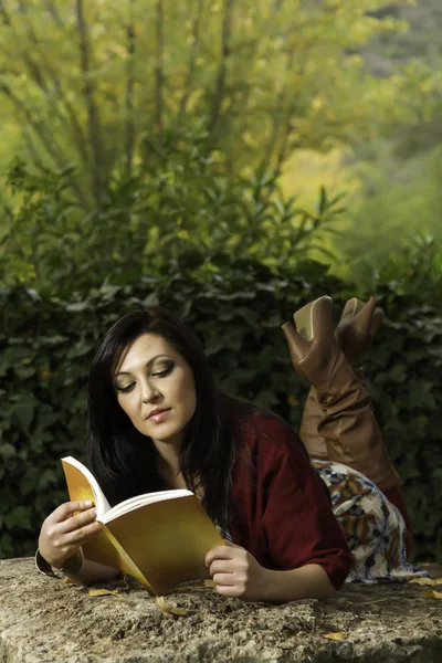 Νεαρή γυναίκα ανάγνωση σε ένα πάρκο — Φωτογραφία Αρχείου