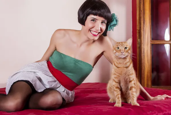 Vue d'une pin-up girl heureuse avec les cheveux courts au lit avec un chat mignon . — Photo