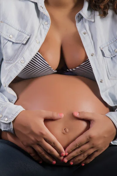 Gravid flicka med händer som bildar ett hjärta form. — Stockfoto