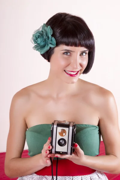 Vista de una chica pin-up en la cama con una pequeña cámara retro . — Foto de Stock