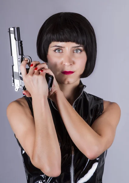 Pin-up fille avec robe sombre et brillante tenant un pistolet . — Photo