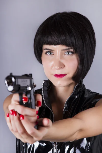Pin-up fille avec robe sombre et brillante tenant un pistolet . — Photo