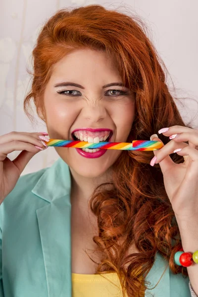 Beautiful redhead girl biting a candy stick — Stock Photo, Image