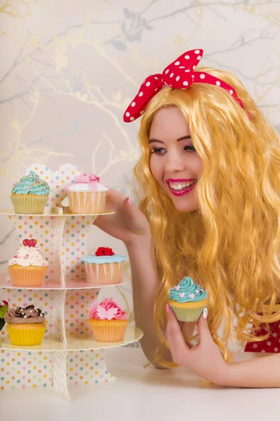 Vackra pinup rödhårig tjej med färgglada cupcakes — Stockfoto