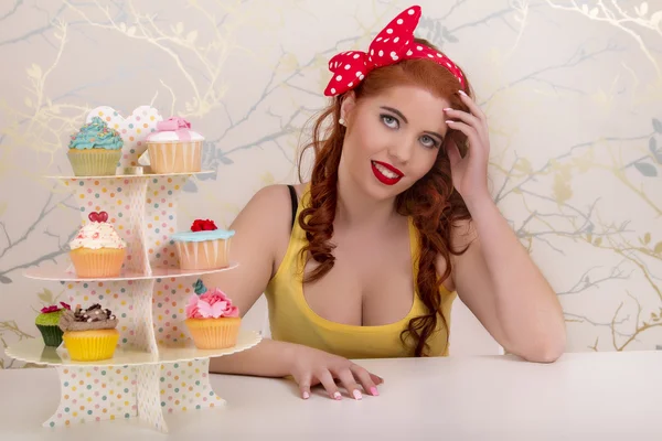 Menina ruiva pinup bonita com cupcakes coloridos — Fotografia de Stock