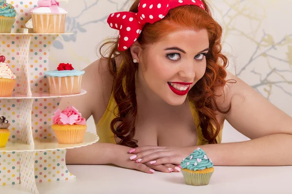Beautiful pinup redhead girl with colorful cupcakes — Stock Photo, Image