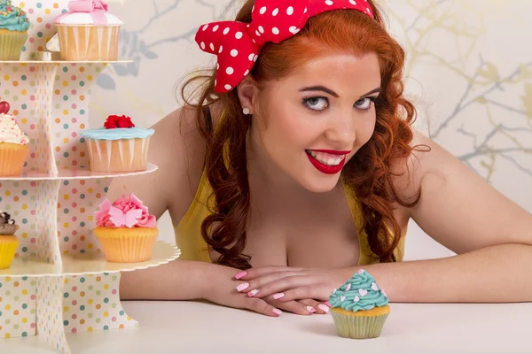 Vackra pinup rödhårig tjej med färgglada cupcakes — Stockfoto