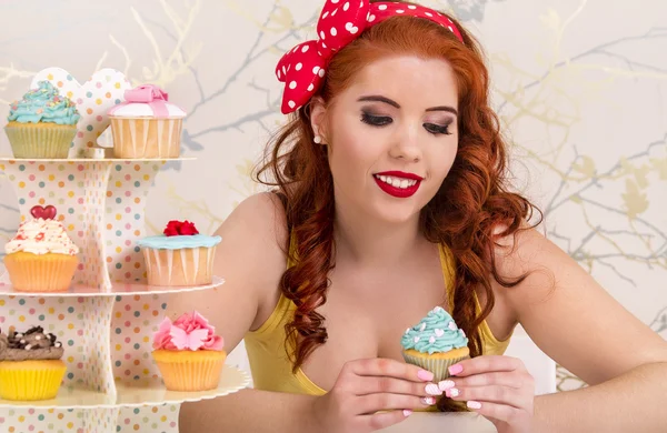 Vackra pinup rödhårig tjej med färgglada cupcakes — Stockfoto