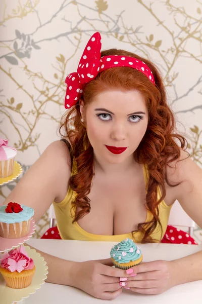 Hermosa chica pelirroja pinup con cupcakes de colores —  Fotos de Stock