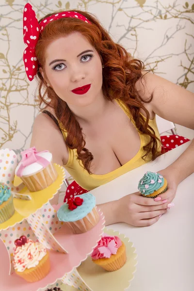 Hermosa chica pelirroja pinup con cupcakes de colores — Foto de Stock