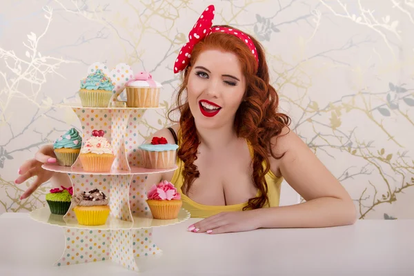 Hermosa chica pelirroja pinup con cupcakes de colores — Foto de Stock