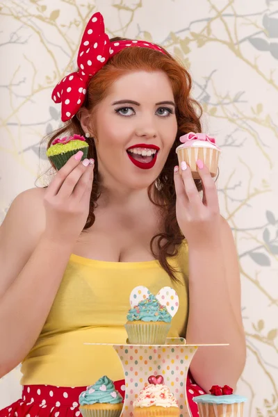 Hermosa chica pelirroja pinup con cupcakes de colores — Foto de Stock