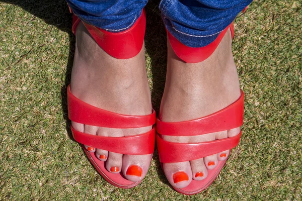 Girls feet with red nails and red sandals — Stock Photo, Image