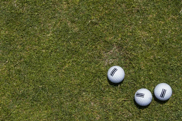 Trois balles de golf sur un coin dans une herbe verte — Photo