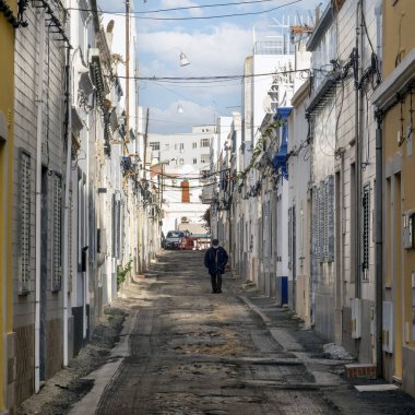 Portekiz 'in Olhao şehrinde sokakların tipik mimarisinde yürüyen yalnız bir figür..