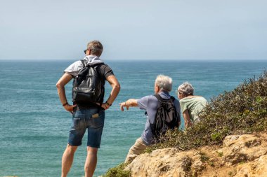 Portekiz 'in Algarve bölgesindeki kıyı şeridi kayalıklarında yürüyüş yapan yaşlılar.