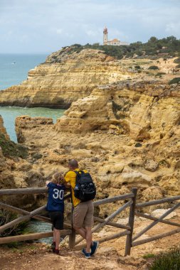 Portekiz 'in Algarve kıyı şeridi bölgesinde Benagil köyü yakınlarındaki güzel uçurumlarda yürüyüş yapan turistler.
