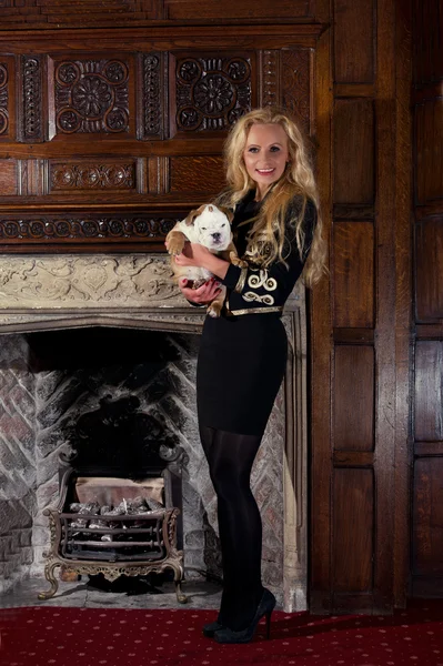 Blonde vrouw met een puppy in Luxekamer — Stockfoto