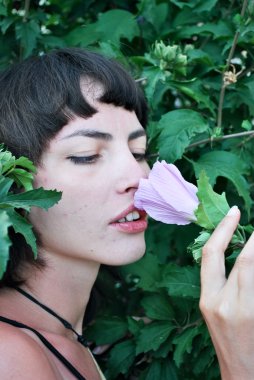 Kız çiçek kokluyor.