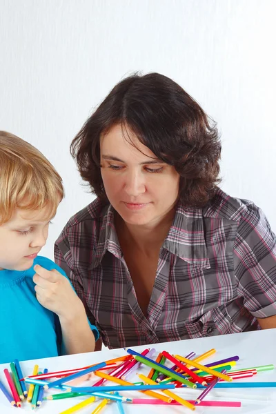 Little cute boy with his mother draws with color pencils