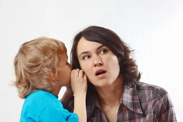 Little boy whispers to his mother something into her ear
