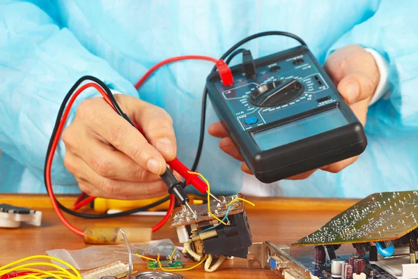 Serviceman checks electronic board with a multimeter