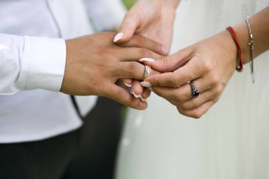 Düğün töreninde, gelin nikah yüzüğünü damadın parmağına takar. Yüzüklü yeni evlilerin elleri. Altın yüzüklerle geleneksel düğün töreni