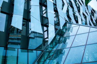 Orijinal mavi dizaynlı cam bina. Gökyüzü yansıması ile Geometrik yüksek bina arka planı. Metin için boş alan. Modern şehir kurumsal gelişimi. Cam bina arkaplanı