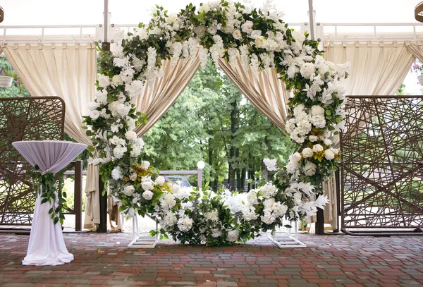 結婚式のための円形のアーチは白い新鮮な花で飾られています 花嫁と新郎の結婚式の準備 伝統的な結婚式のための美しい装飾 — ストック写真