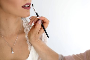 Makyöz genç bir geline makyaj yapar. Profesyonel bir makyöz, bir kadının dudaklarına fırçayla ruj sürer. Gelinin dudaklarına yakın bir fırçayla makyaj sanatçısı. Metin için boş alan