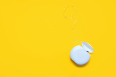 Sarı arka planda diş temizliği için diş ipi. Ağız bakımı ve bakımı önleme kavramı. Diş bakımı ürünleri ve ağız hijyeni. Metin için boş alan