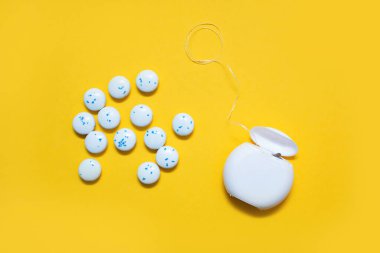 Diş ipi ve nane aromalı yuvarlak sakız çiğneme sarı arka planda. Ağız bakımı ve bakımı önleme kavramı. Diş bakımı ürünleri ve ağız sağlığı ürünleri