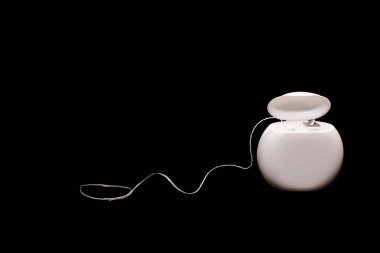 Siyah arka planda diş temizliği için diş ipi. Ağız bakımı ve bakımı önleme kavramı. Diş bakımı ürünleri ve ağız hijyeni. Metin için boş alan