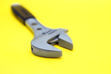 Sarı arka planda, modern ayarlanabilir İngiliz anahtarı. Tamir ya da inşaat için kullanılan bir araç. Boruları ve fındıkları onarmak için özel bir araçName