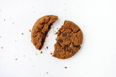 Bir çikolatalı kurabiye beyaz arka planda kırıntıları olan iki parçaya bölündü. Lezzetli ev yapımı Amerikan kurabiyeleri. Vejetaryenler için sütle lezzetli bir kahvaltı.
