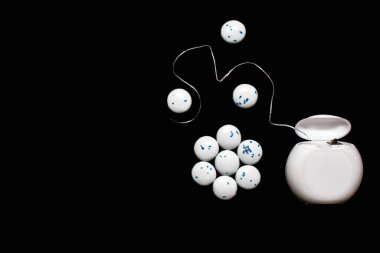 Diş ipi ve nane aromalı yuvarlak sakız çiğneyen siyah bir arka plan. Ağız bakımı ve bakımı önleme kavramı. Modern diş bakımı ve ağız hijyeni