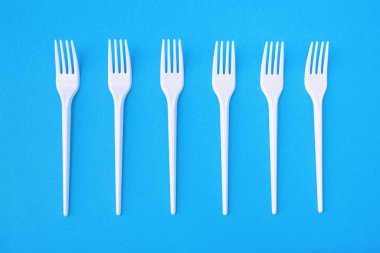 Tek kullanımlık mavi bir arka planda altı plastik çatal. Çevre için tehlikeli bir plastik. Tek kullanımlık yemek tabakları