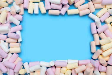 Küçük renkli bir marşmelov mavi bir arkaplan üzerine çerçeve şeklinde serilir ve metin veya reklam için boş bir alan bırakır. Şeker satma ya da kahve dükkanı reklamı yapma fikri.