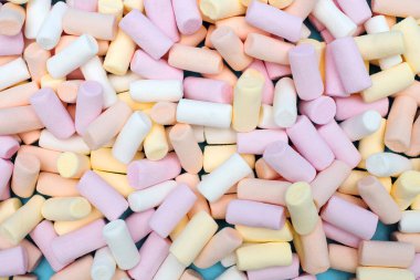 Çok renkli marşmelovlar mavi arka plana saçılmış. Lezzetli tatlı ya da kakaoya ya da sıcak çikolataya eklenen şekerleme. Çocuklar için tatlı çiğnemek. Şekerlemelerin arkaplanı