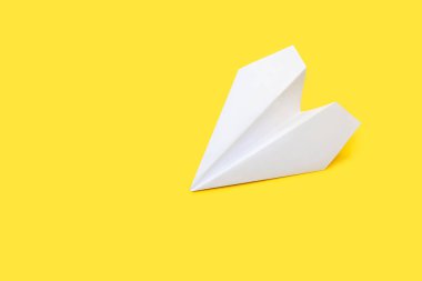 Sarı arka planda beyaz kağıt uçak. Kağıt origami sarı karton arka planda küçük bir uçak şeklinde. Seyahat ya da karar özgürlüğü kavramı. Metin için boş alan