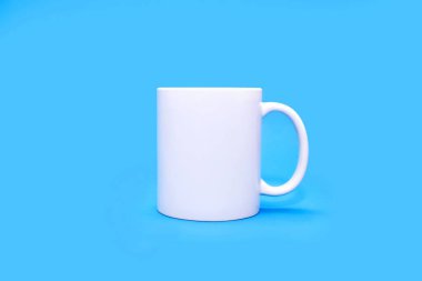 Merkezde mavi arka planda beyaz bir kupa. Boş mavi arka planda herhangi bir içeceği olan beyaz bir kupa. Kafe ya da atıştırmalık konsepti. Reklam veya logo ihtimali olan beyaz bir kupa.