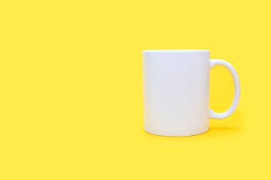 Sarı arka planda beyaz kupa ve mesaj için boş yer var. Boş sarı arka planda beyaz bardak ve bir içki. Kafe ya da atıştırmalık konsepti. Reklam ya da logo kullanma ihtimali olan beyaz kupa.