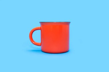 Mavi arka planda, yazı için boş yeri olan turuncu bardak. Mavi arka planda bir içki ile turuncu fincan. Kafe ya da atıştırmalık konsepti. Reklam veya logo uygulama olasılığı olan turuncu kupa.