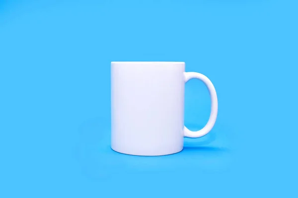 中间是蓝色背景的白色杯子 一种白色杯子 任何饮料都可以放在蓝色的空背景上 咖啡或小吃的概念 有可能做广告或标志的白色杯子 — 图库照片