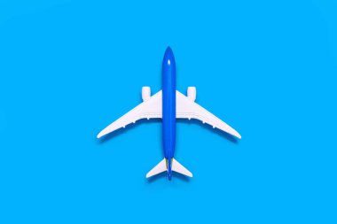 Görüntünün merkezinde mavi bir arka planda uçak modeli. Turizm ya da nakliye konsepti. Mavi arka planda, üst manzaralı oyuncak uçak.