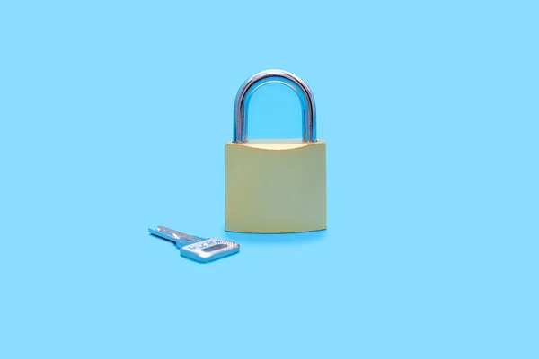 蓝色底座上有钥匙的闭锁 金黄色锁 蓝色背景上有银匙 以锁的形式提供保护和安全的概念 — 图库照片