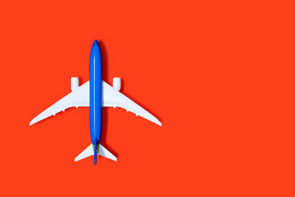 Aircraft model on an orange background with free space for text or advertising. The concept of tourism or cargo transportation by plane. Top view toy airplane on orange background