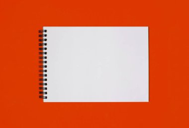 Beyaz kağıttan yapılmış, turuncu kaplamalı bir defter. Metin için boş alanı olan notsuz boş not defteri. Yatay bir fotoğrafta işaretsiz klasik bir dizin.