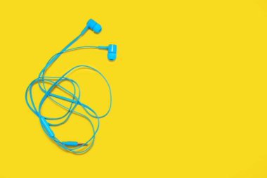 Sarı arka planda karışık kulaklıklar var. Mavi kulaklıklar bükülmüş ve onları çözmek büyük bir sorun. Metin için düğümlü taşınabilir kulaklıklar